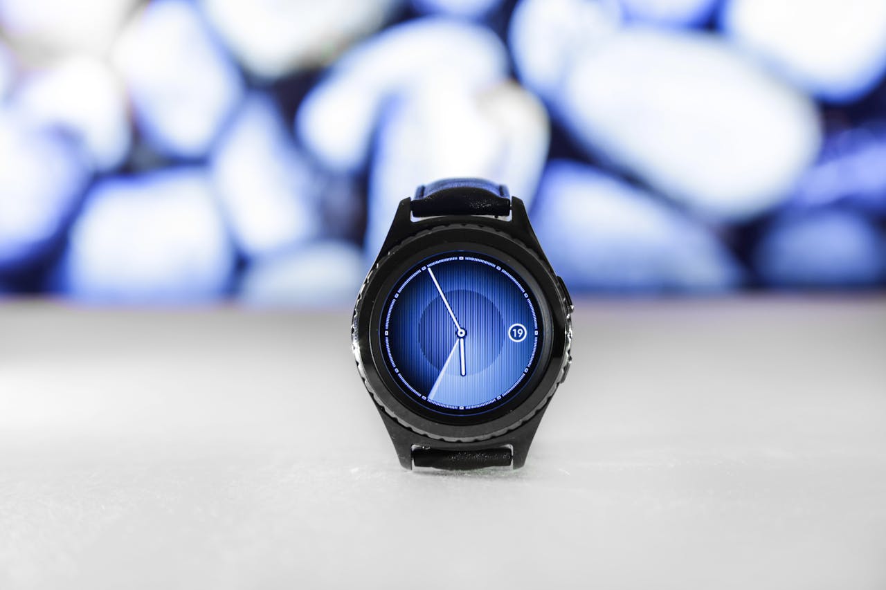 A sleek digital smartwatch with a blue interface against an abstract blurred background. Stylish and modern.